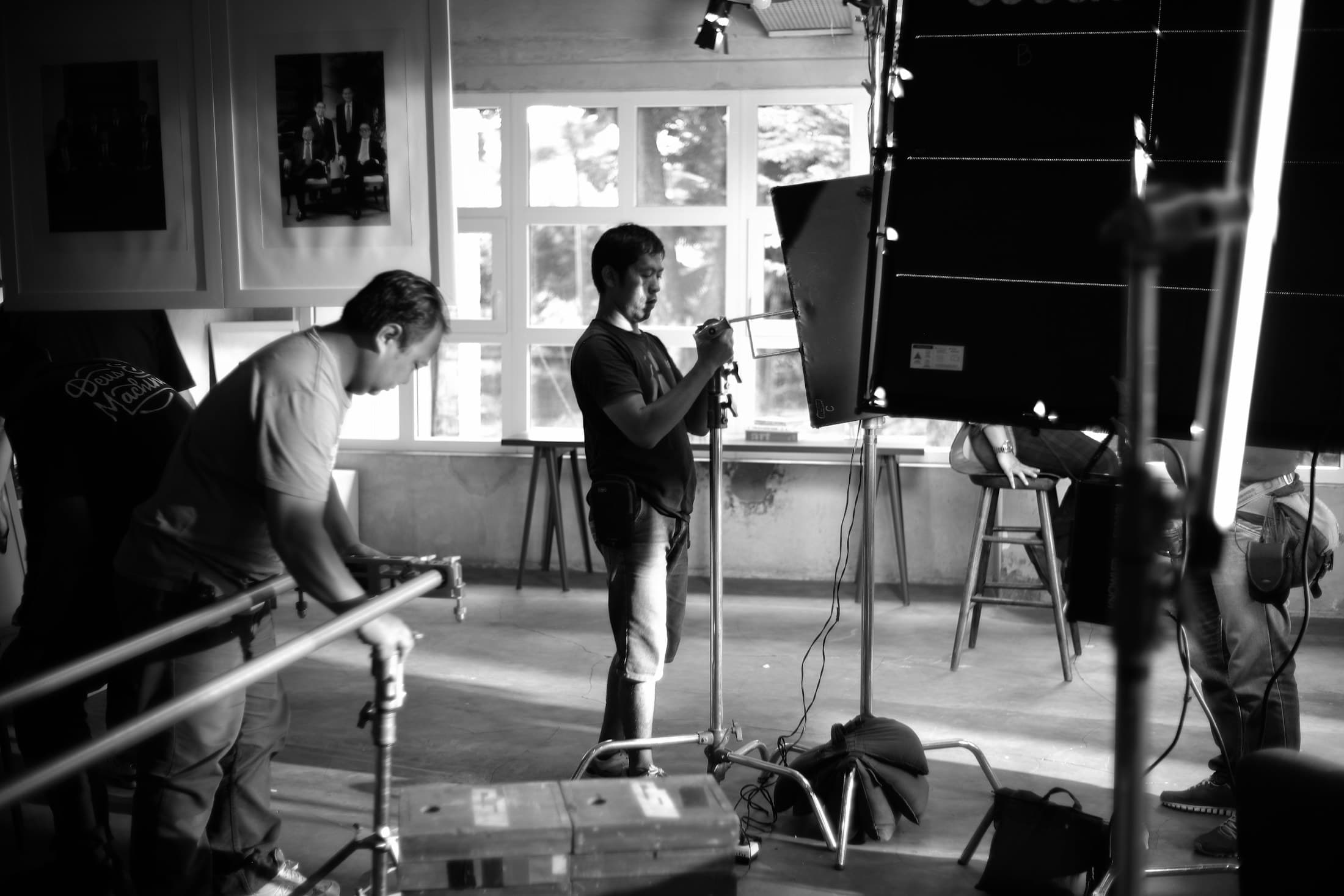 Film crew members arranging lighting and camera support in a studio